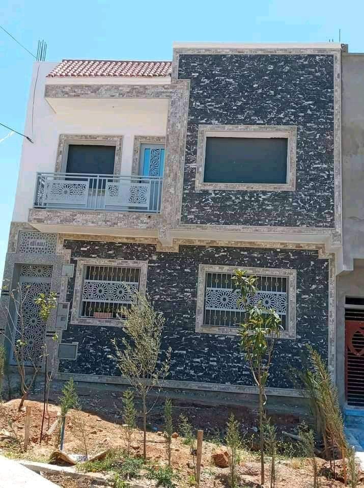 Façade avec granit noir posé d'un côté et enduit brut de l'autre