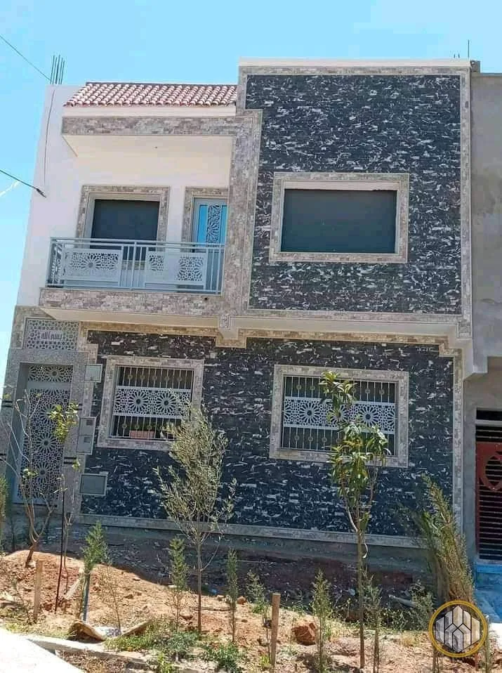 Façade avec granit noir posé d'un côté et enduit brut de l'autre